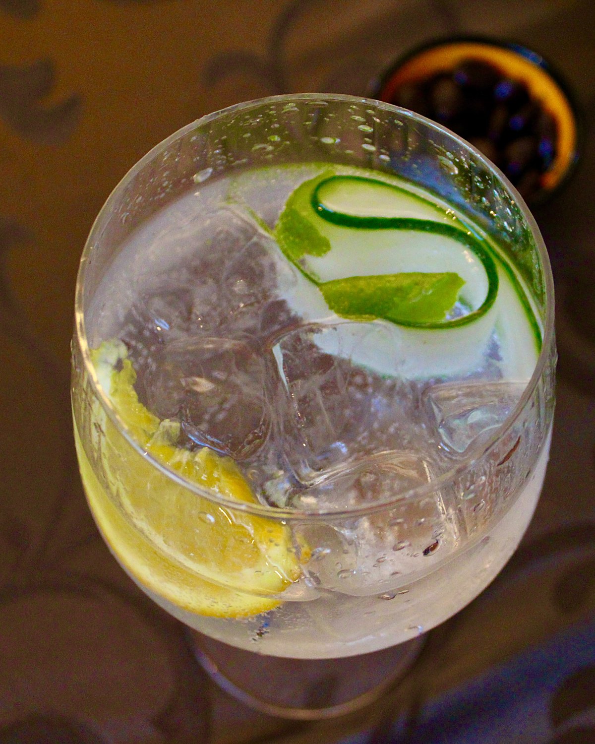 Gin-tonic met komkommerlint, citroen en munt, van bovenaf